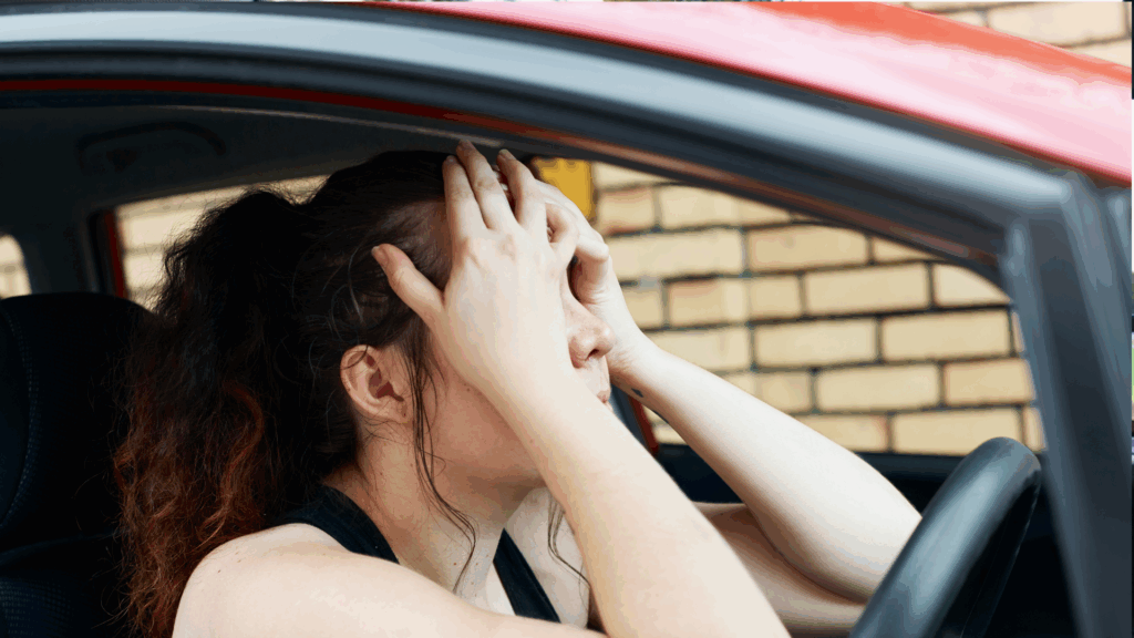 Fahrerin im Auto hält gestresst den Kopf – Symbolbild für Sorgen rund um Punkte in Flensburg und deren Verfall.